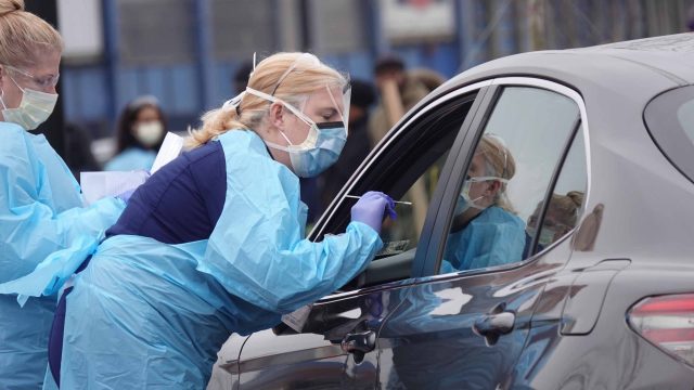 A man prepares for a mouth swab at a drive-through coronavirus testing site for residents who have symptoms and an order from a health care provider on Quincy Street in Arlington, Virginia, on Thursday, March 19, 2020